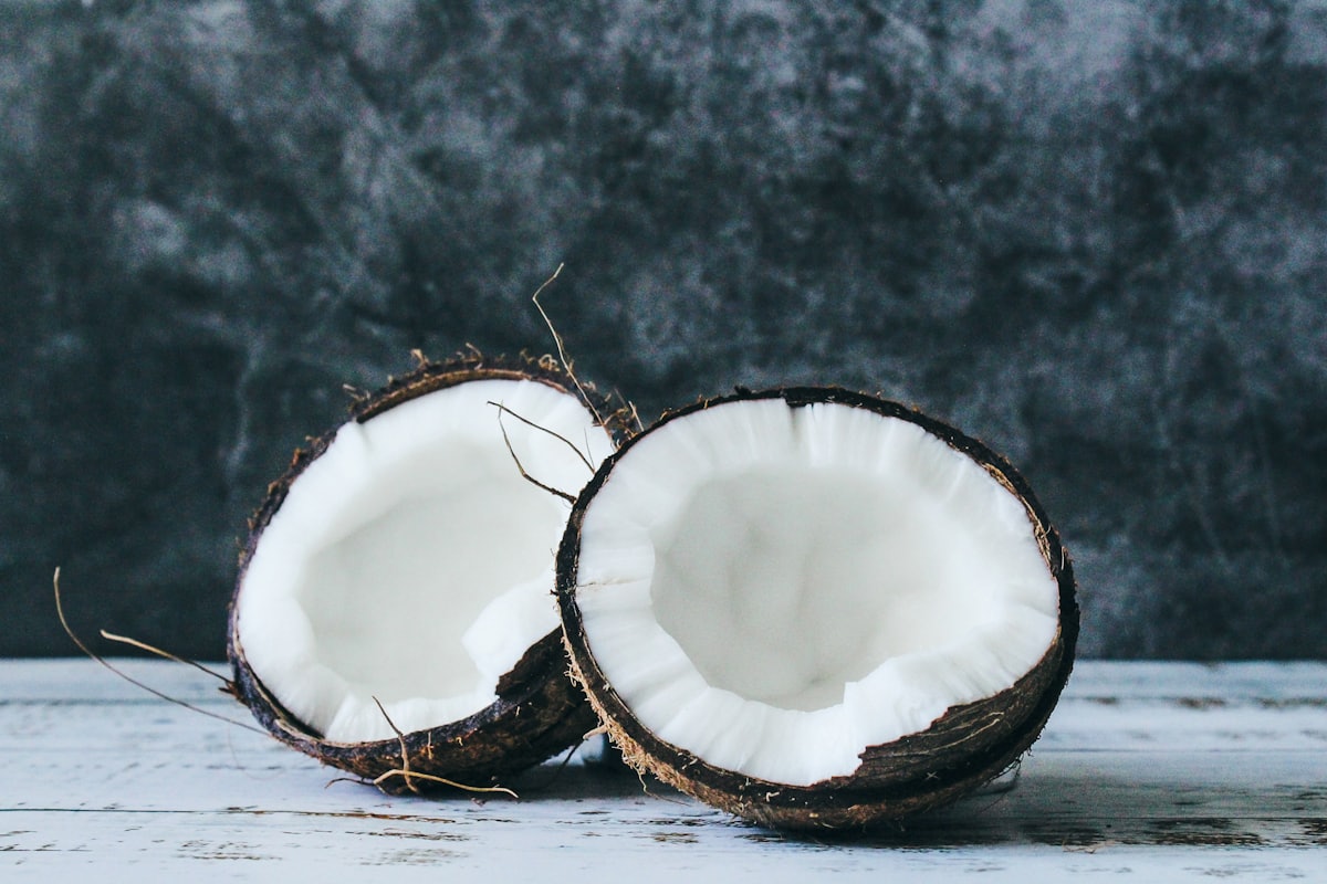 A bowl of coconut milk beside fresh aromatics