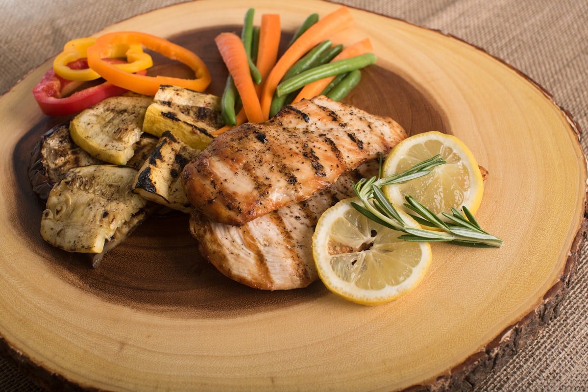 A whole fried fish topped with sweet-sour sauce, red and green bell pepper strips, carrots, and ginger