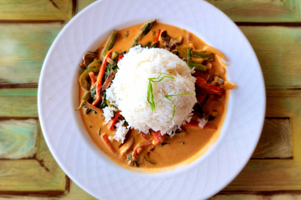 A pot of ginataang gulay with orange squash chunks, green string beans, and leafy greens in creamy coconut milk